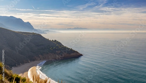 Gentle cliffs and a calm shoreline stretch beneath a hazy horizon, evoking a sense of tranquil coastal beauty.