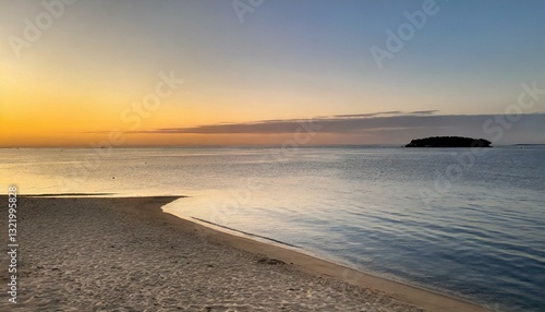 A wide, sunlit beach with gentle waves rolling under a pale sky, conveying calm and minimal coastal beauty.