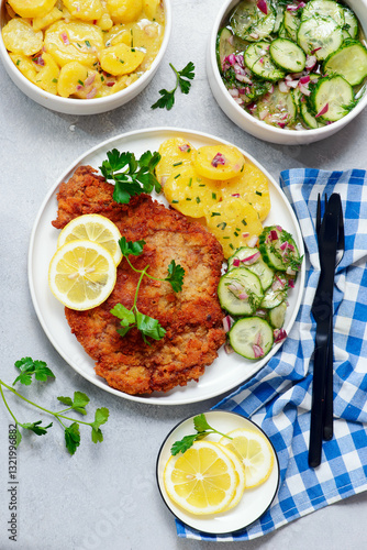 Traditional Viennese schnitzel on a plate with cucumber and potato salad.selective focus