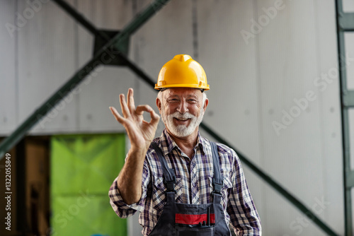 Portrait of senior industry worker standing in facility and gesturing okay at the camera. photo