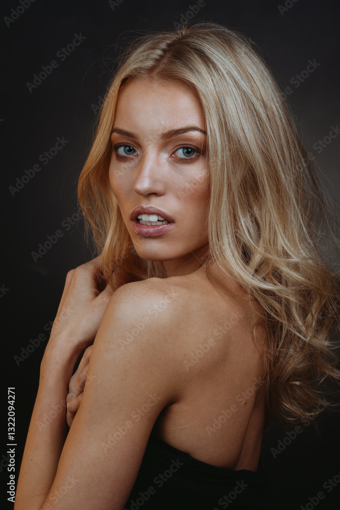 Naklejka premium Serene Blonde Vision: Blue-Green Eyes and Flowing Hair on Dark Canvas