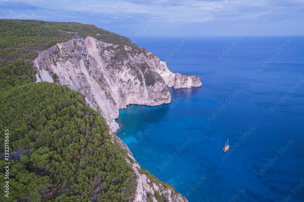 Fototapeta premium Sail through the crystal-clear turquoise waters of Zakynthos as cliffs rise dramatically from the Ionian Sea. Experience the tranquil beauty of Greek nature during sunset, surrounded by olive groves