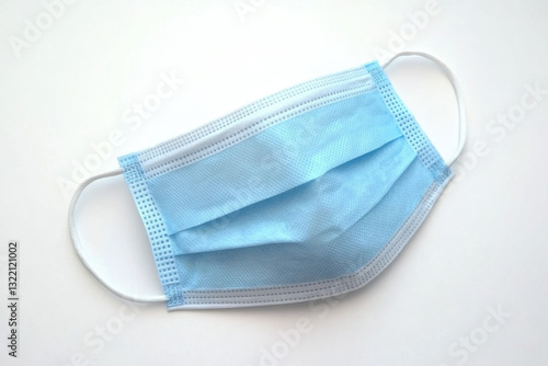 Disposable blue surgical mask neatly folded on a seamless white background for medical use and protection against contaminants photo