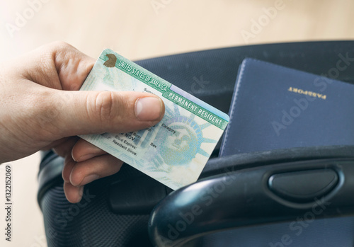 Man holding permanent resident (green) card. United States passport   on suitcase. Application to register permanent residence.