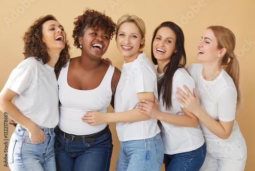 Принти на полотні Group portrait of diverse women in casual white t shirts gather together and have fun, laugh at something funny, feel overjoyed, isolated over beige studio background