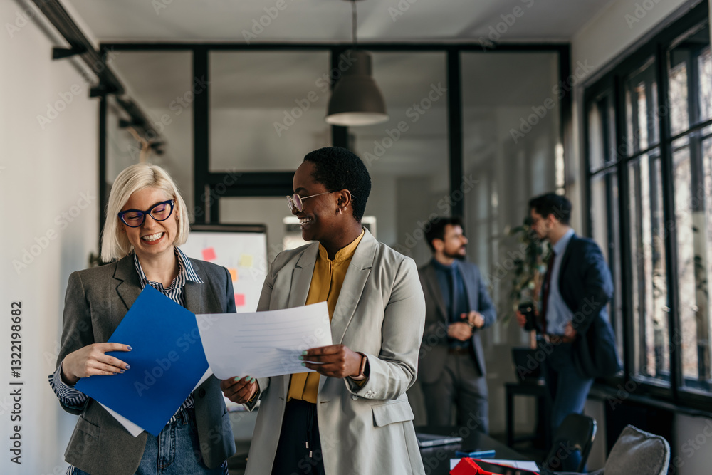 Professional coworkers standing and working on paperwork at a bright office Professional coworkers standing and working on paperwork at a bright office