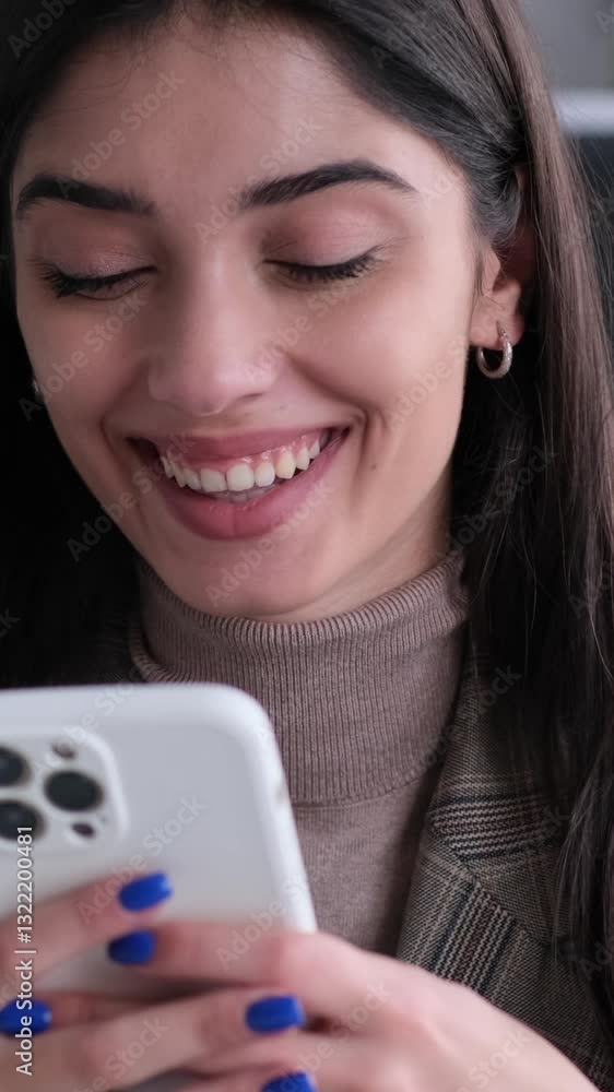 Happy Caucasian young adult businesswoman using phone for online entertainment and laughing during break in the office. Vertical video. Happy Caucasian young adult businesswoman using phone for online entertainment and laughing during break in the office. Vertical video.