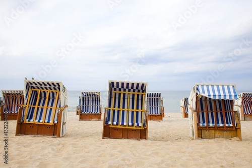 Fototapeta Naklejka Na Ścianę i Meble -  Traditional wood and wicker beach baskets, lined in white-blue stripes, dot Kolobrzeg’s shore with the Baltic Sea in view.