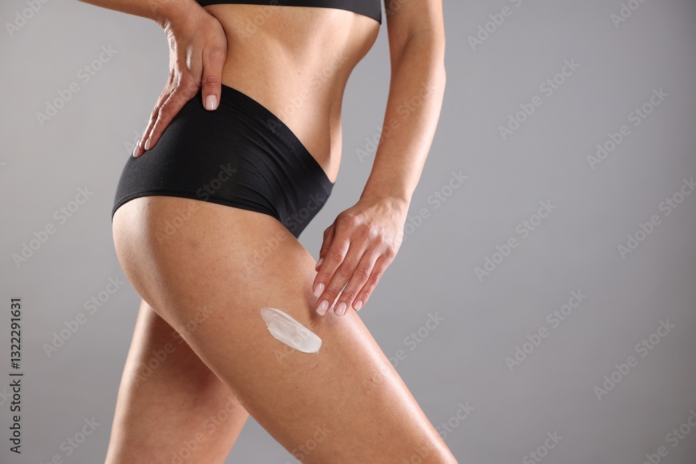 Fototapeta premium Woman applying anti cellulite cream on grey background, closeup