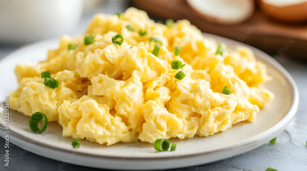 Fluffy scrambled eggs on a white plate symbolize simplicity and comfort in breakfast cuisine with a minimalistic bright tone and blurred empty caption space on the side Fluffy scrambled eggs on a white plate symbolize simplicity and comfort in breakfast cuisine with a minimalistic bright tone and blurred empty caption space on the side