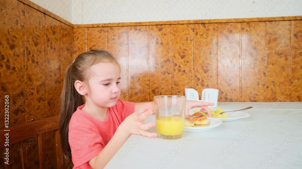Little girl eats pancakes with juice at the kitchen table Little girl eats pancakes with juice at the kitchen table