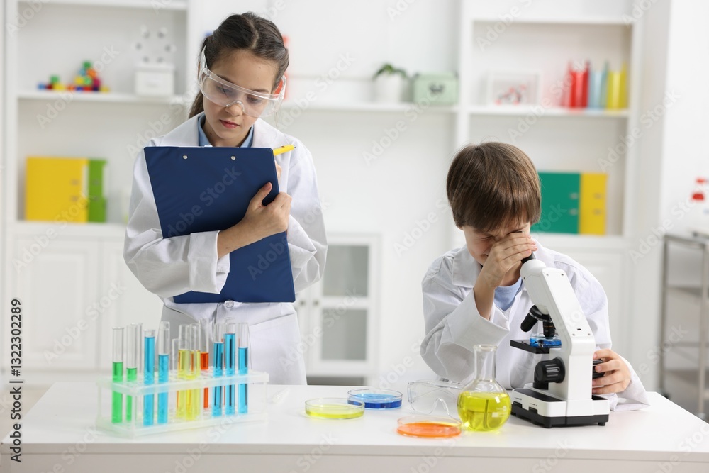 Children doing chemical experiment at desk indoors Children doing chemical experiment at desk indoors