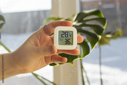 Konstfotografi Woman holds small digital indoor temperature and humidity meter