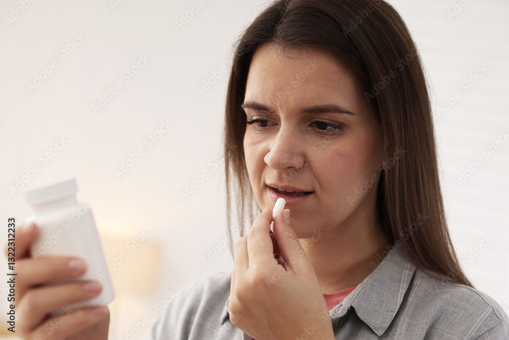 Woman reading medical instruction on plastic bottle while taking pill at home Woman reading medical instruction on plastic bottle while taking pill at home