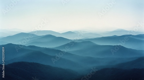 Rolling blue mountains fade into the misty horizon, creating a serene and endless landscape, embodying tranquility and natural beauty.