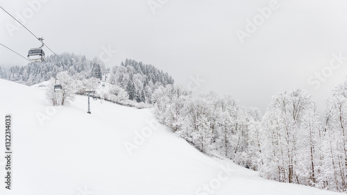 Obraz na płótnie Winter landscape with snowy trees and a gondola railway to the top of the mountain, view during a mountain hike on a hiking trail. Winter day with cloudy and foggy weather. w salonie