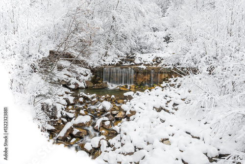 Obraz na płótnie Mountain river in winter, water flows down the riverbed over snow-covered rocks. Winter landscape on a mountain hiking trail. w salonie