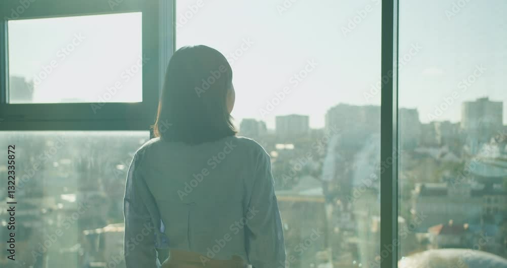 A thoughtful professional gazing out at a sprawling urban cityscape from a modern office window, symbolizing ambition, reflection, and possibilities