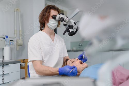 Photos Male dentist doing dental procedure in dental clinic, using dental microscope