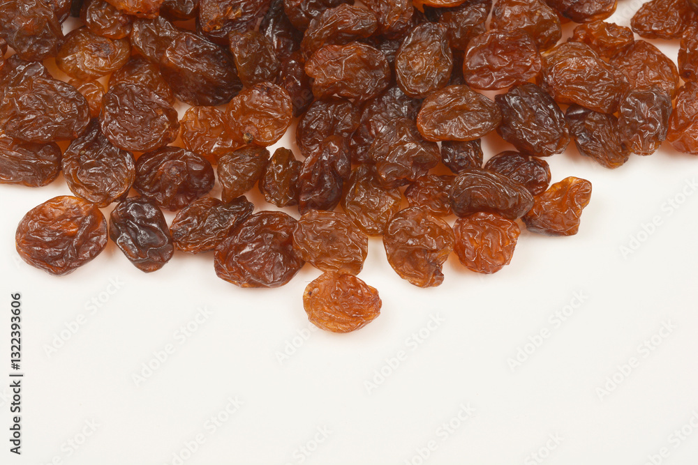 A top-down shot of a scattering of dark brown raisins on a light surface A top-down shot of a scattering of dark brown raisins on a light surface