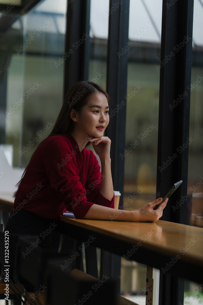 Obraz premium Thoughtful Woman with Tablet by Window