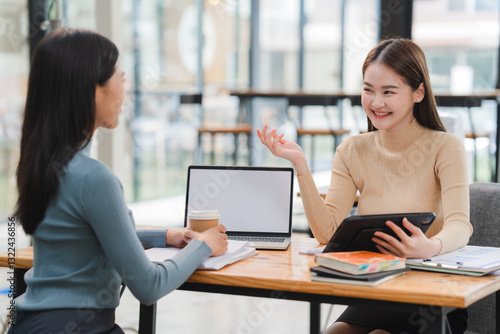 Two Young Women Discussing Business in Modern Office