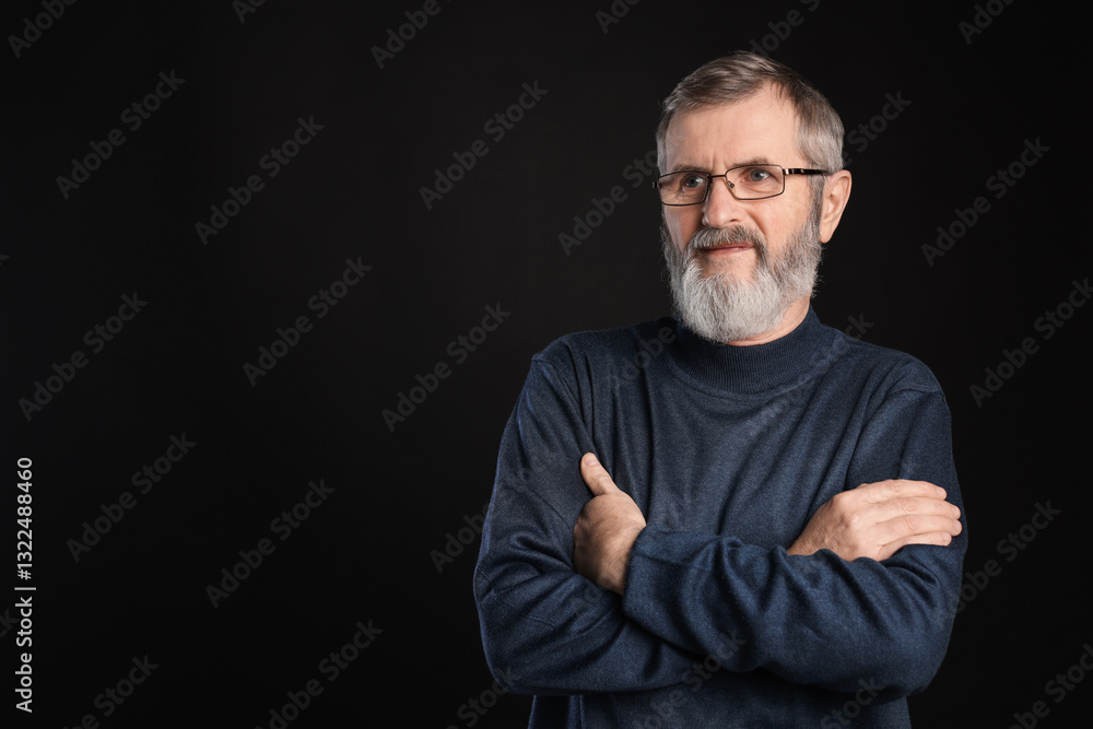 Fototapeta premium Portrait of mature man with crossed arms on black background, space for text