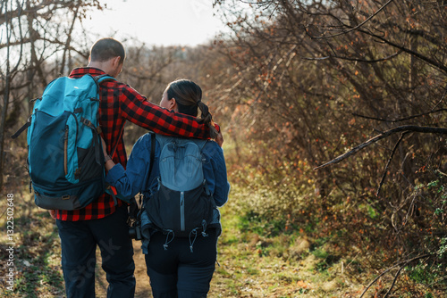 Wallpaper Mural Hikers walking along a forest trail enjoy a sunny day, with a man embracing a woman as they share a moment of love and connection while carrying their backpacks Torontodigital.ca
