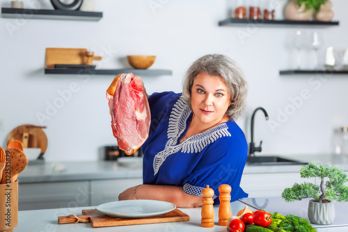 Beautiful senior woman holding a piece of fresh juicy meat tenderloin while cooking in the kitchen. Healthy and organic eating. Vitamin foods are good for your health.	