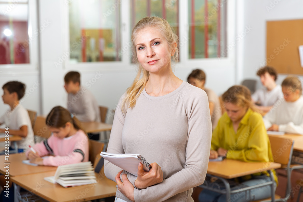 Waist-up portrait of female teacher standing in classroom during lesson. Waist-up portrait of female teacher standing in classroom during lesson.