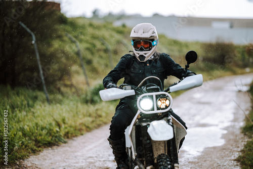 Obraz na płótnie Motorista creando contenido en dia lluvioso en camino de barro inundado w salonie