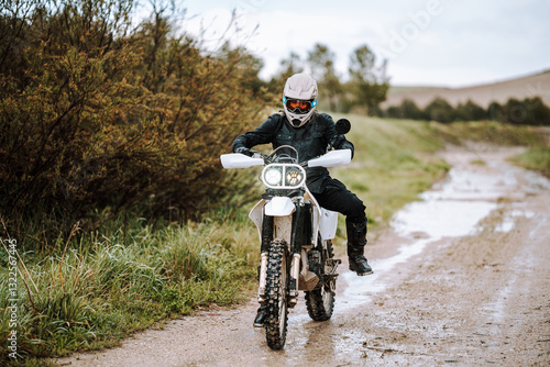 Obraz na płótnie Motorista creando contenido en dia lluvioso en camino de barro inundado w salonie