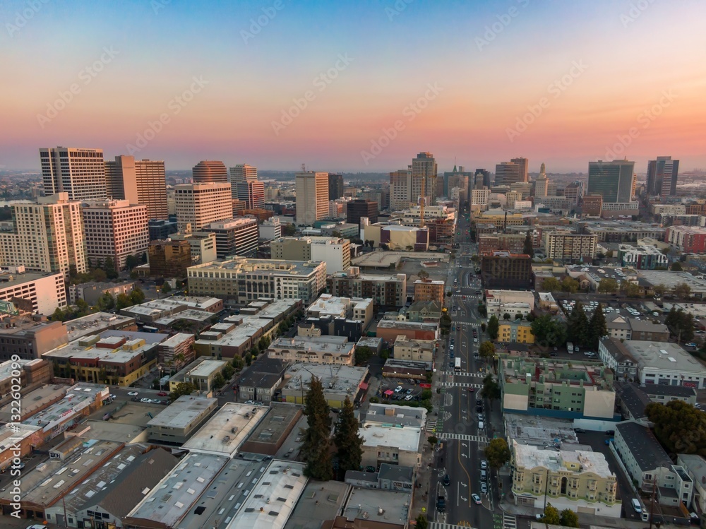 Fototapeta premium Aerial view of Oakland, California, USA, at sunset. The photo shows the city's skyline, streets, and buildings, capturing the urban landscape and the transition from day to night.