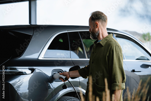 The man connects the charging to the electric car
