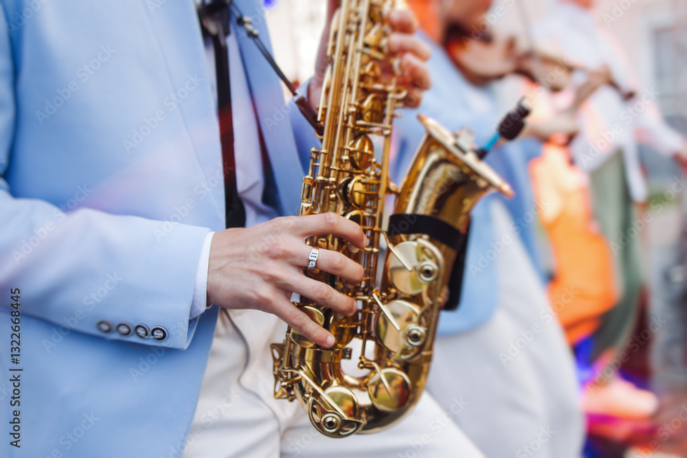Fototapeta premium Concert view of saxophonist musician, saxophone sax player with vocalist and musical band during jazz orchestra show performing music on a stage in the scene lights, concert in a musical club hall