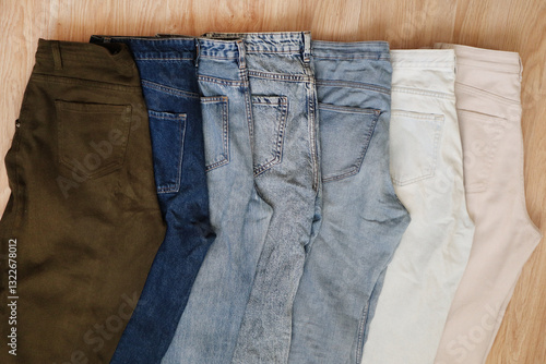 A row of folded trousers and jeans in various shades