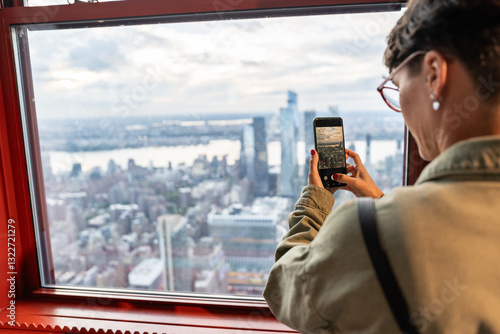 Woman capturing cityscape view using smartphone from observation point