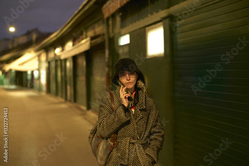 Woman makes a phone call  wearing a striped coat at dusk in Vienna photo