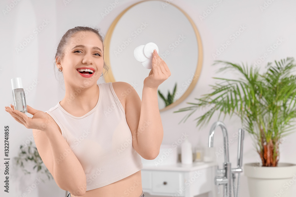 Beautiful young woman with micellar water and cotton pads in bathroom Beautiful young woman with micellar water and cotton pads in bathroom