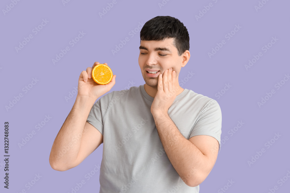 Young man with orange suffering from toothache on lilac background Young man with orange suffering from toothache on lilac background