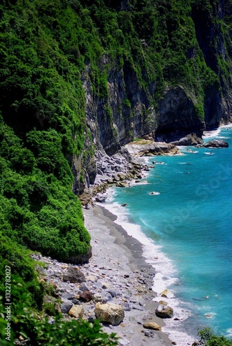 grey sand beaches over sheer tropical mountain cliffs, and bright blue ocean water