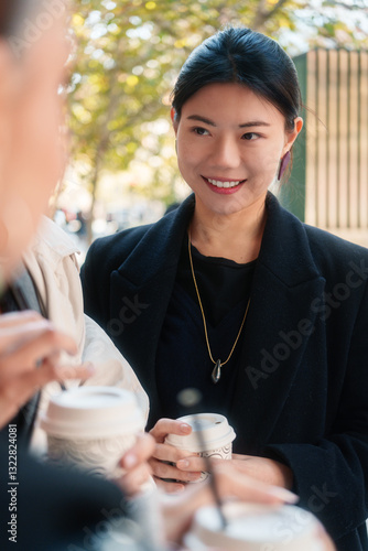 Woman smiling and holding a coffee cup while engaging in conversation photo