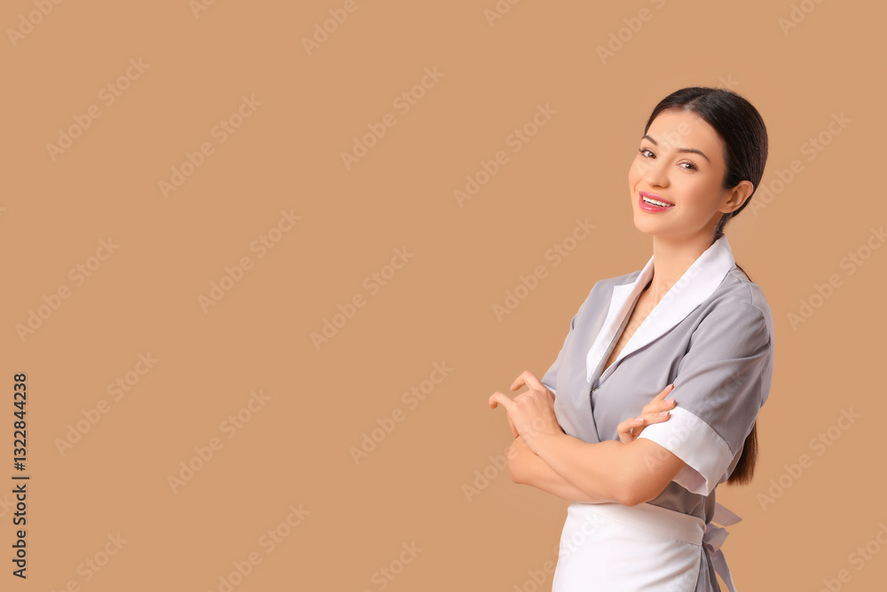 Beautiful young chambermaid on beige background
