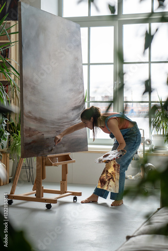 Concentrated female artist drawing picture working on art project at home. Focused woman creatively transfering emotions feelings to canvas with brushes, oil creating masterpiece. Art therapy