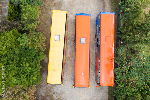 Colorful Buses Parked in Lush Greenery and Gravel Area photo