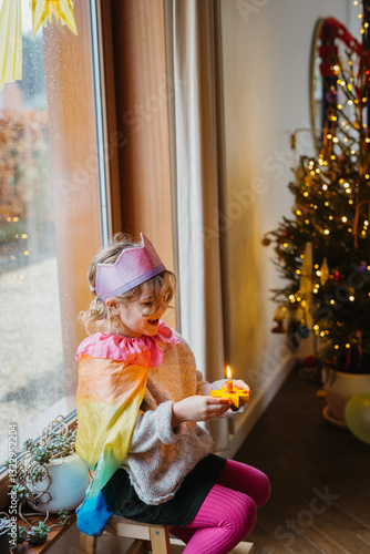 child in colorful attire, gleefully holding a burning candle. photo