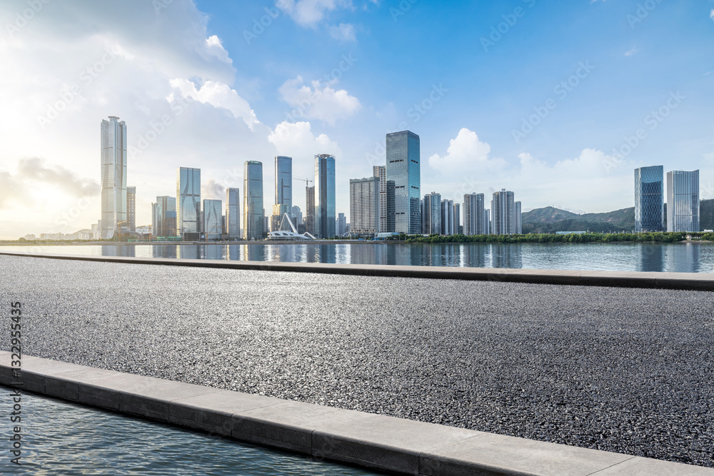 Empty asphalt road platform and lake with modern city buildings background