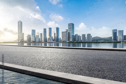 Obraz na płótnie Empty asphalt road platform and lake with modern city buildings background w salonie