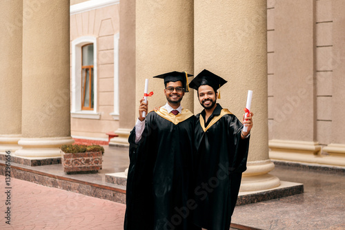 Indian men wearing graduated uniform holding diplomas at university. photo