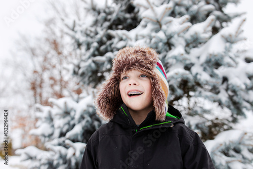 portrait of a boy in front of a snowy spruce tree photo